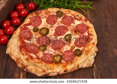 Homemade fresh delicious gourmet pizza whit spicy salami and jalapeno pepper ,Tasty italian pizza isolated on wooden table,Close up with selective focus