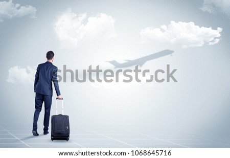 Young businessman with luggage walking towards an looking to a raising airplane