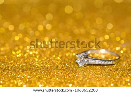 Ring with diamonds on a golden radiant background. Glitter shine with engagement ring