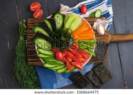 Raw vegan buddha bowl with fresh vegetables on wooden board. Cucumber, tomatoes, carrot, seaweed, radish, capsicum, flax flatbread. Vegetarian healthy food