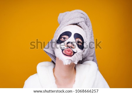 funny young girl with a towel on her head, on her face a useful mask with a picture of a muzzle of a panda