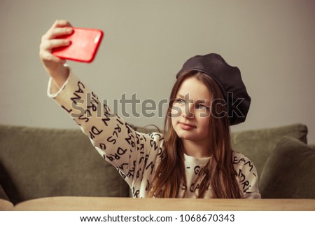 simpotical girl teenager posing in cafe, making selfie on phone in red case, model with long hair and black leather biret, cafe, lifestyle