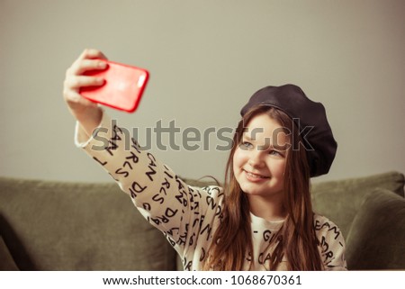 simpotical girl teenager posing in cafe, making selfie on phone in red case, model with long hair and black leather biret, cafe, lifestyle