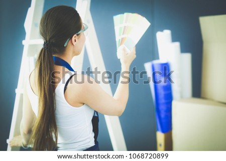 Young woman holding a color swatch with a painter painting