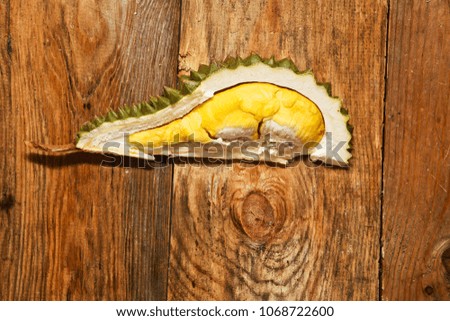 Yellow durian with thorny shell on wooden floor.