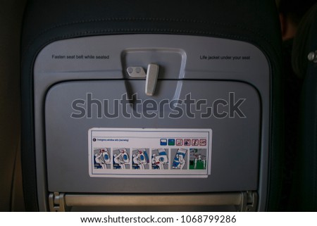 Sign and safety information instruction  card on a plane display at passenger back seat