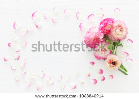 Image of delicate pastel pink beautiful flowers arrangement over white wooden background. Flat lay, top view