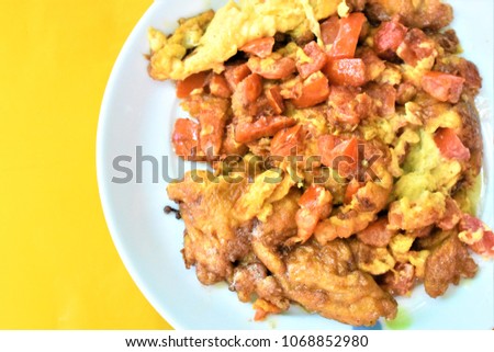 Thai omelette with tomato on plate on yellow background.