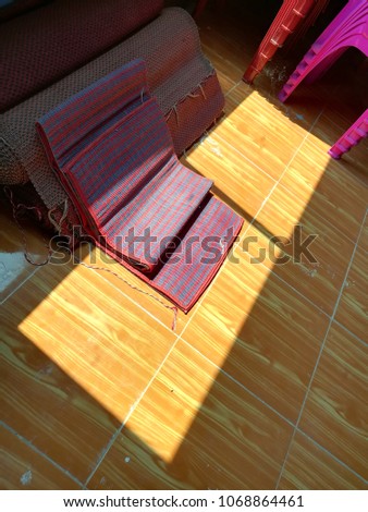 Blue - red  woven mats placed near the window with sunlight.