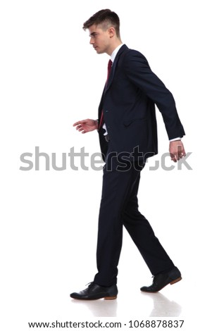 side view of businessman dressed in navy suit walking on white background and looking down at something, full body picture