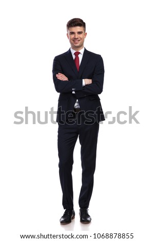 happy businessman standing on white background with arms folded, He is wearing a navy coloured suit and a red tie, full body picture