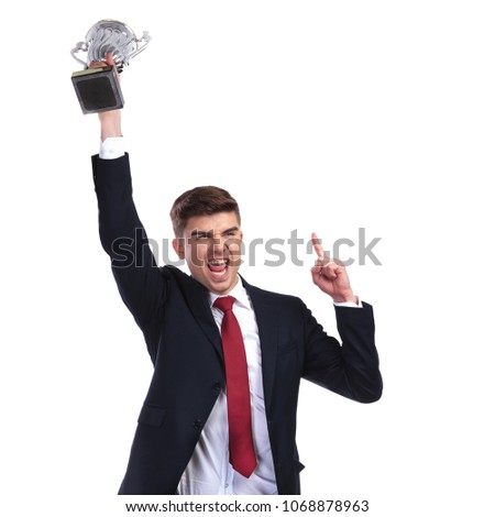 Champion businessman holding trophy and pointing finger up while standing on white background, excited to be a winner