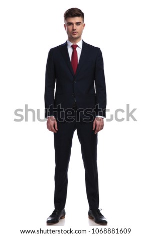 handsome businessman posing while standing on white background, wearing a navy suit and a red tie, full body picture