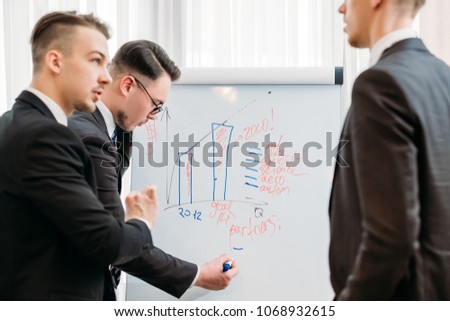 business briefing and goals visualization. company managers writing on the flip chart in office board room