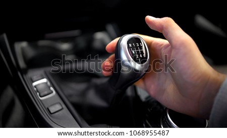 Male hand holding manual gearbox in car, test drive of new automobile, closeup Royalty-Free Stock Photo #1068955487
