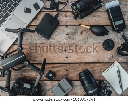 top view of work space photographer with drone, digital camera, memory card, external harddisk and camera accessory on wooden table background with copy space.