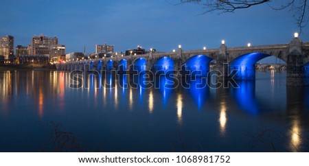 Market Street Bridge in Harrisburg PA at dusk with blue lights under the bridge reflecting on the river