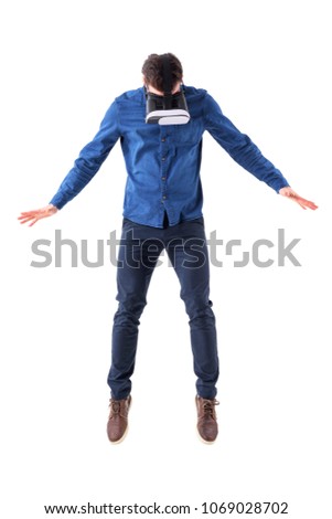 Surprised man wearing vr glasses jumping and looking down having virtual reality experience. Full body isolated on white background.