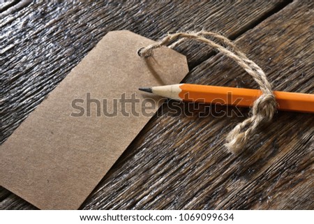 A close up image of a brown gift tag and single sharpened pencil. 