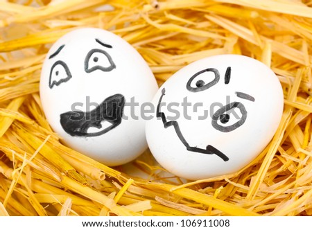 White eggs with funny faces in straw