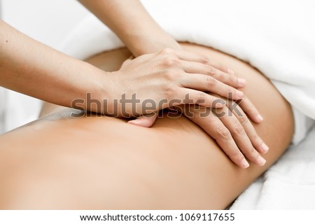 Young woman receiving a back massage in a spa center. Female patient is receiving treatment by professional therapist. Royalty-Free Stock Photo #1069117655