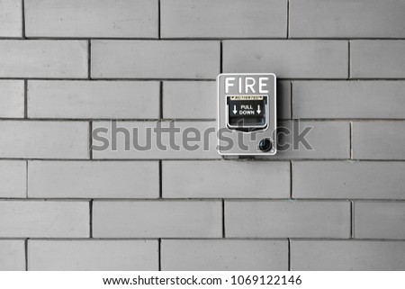 fire alarm switch at grey brick wall inside the motel building