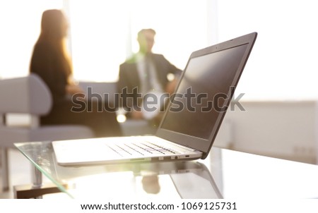 Focus on laptop on the table. Blurred people on background.