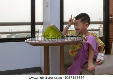 Allergy sickness Asian black hair boy with happiness and big smile background. Alone 4 year old patient kid in hospital room using tablet video call to school and talking with his teacher and friends