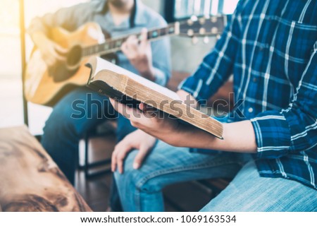 close up of a man holding hymn books and sing a song while his friend playing guitar, praise and worship concept Royalty-Free Stock Photo #1069163534