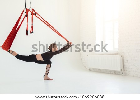 Young slim woman practicing fly yoga asana and stretching over white background in fitness gym, copy space. Health, sport, yoga concept