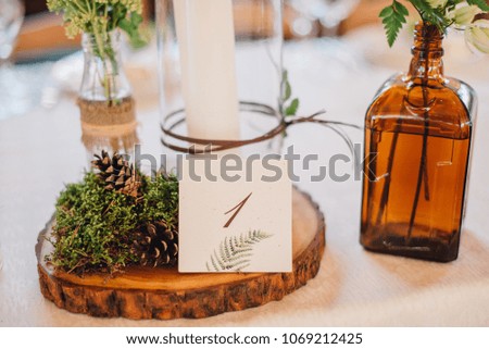 White dinner table served with wooden decor, fern and candles