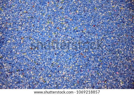 Texture of a colored granular sand close up. Blue grains