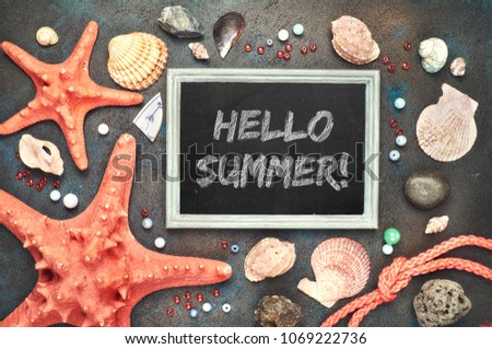 Blackboard with "Hello Summer!" chalk text, with sea shells, rope and star fish on dark background