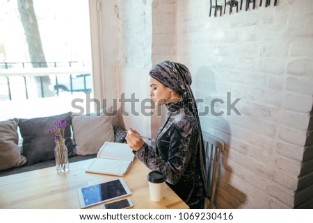 Muslim woman writing love diary in cafe