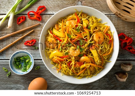 Delicious Singapore style noodles with curry, shrimp, bbq pork, carrots, red pepper, onion and scallions. Royalty-Free Stock Photo #1069254713