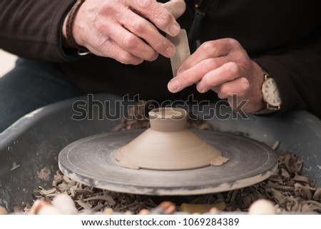 artisan potter makes earthenware pot on wheel using various tools