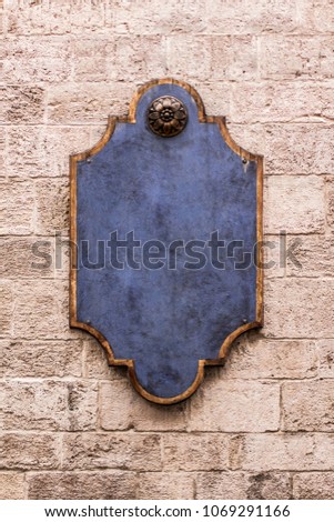 Old blue rustic wooden signboard on the stone wall. Place for text and logos