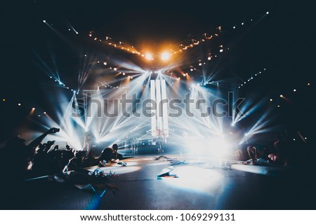 illuminated concert club stage 
silhouettes of concert crowd in front of bright stage lights. Dark background, smoke, concert  spotlights Royalty-Free Stock Photo #1069299131