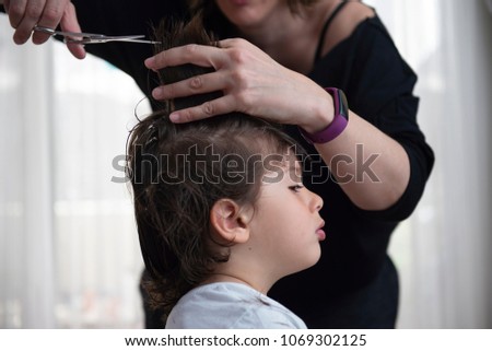 boy cutting his hair for his mother