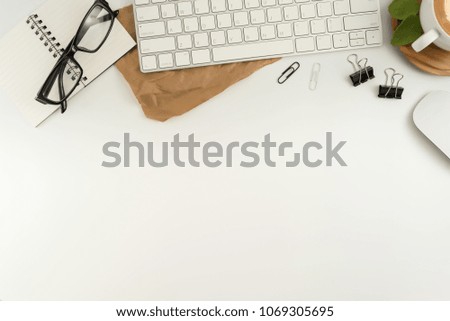 Flat lay, top view office table desk. Workspace with blank note book, keyboard, macaroon, office supplies, flowers, green leaf and coffee cup on white background.