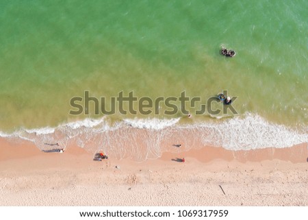 Aerial view of beach with tourists, playing, working and relaxing