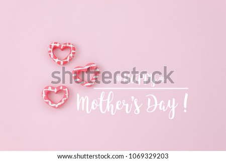 Top view aerial image of decoration Happy mothers day holiday background concept.Flat lay mom text with red heart on modern beautiful  pink paper at home office desk.Free space for creative design.