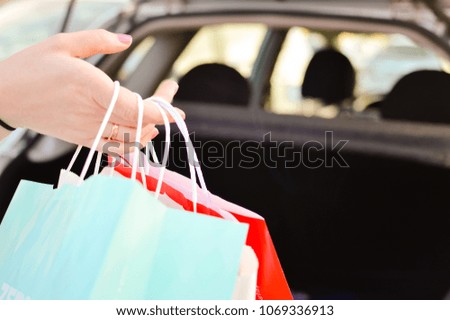 Close up on hand of a woman hold paper bag doing shopping over busy lifestyle background. Modern consumerism, buying, spending trend and marketing solution