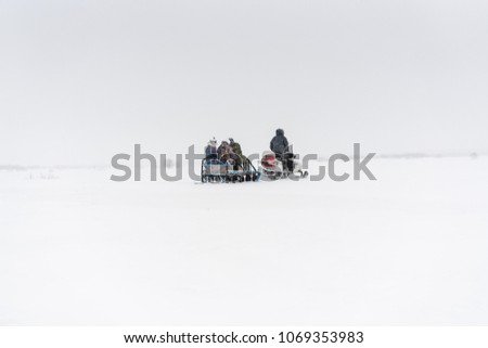 Snowmobile with people in a sled driving through the blizzard