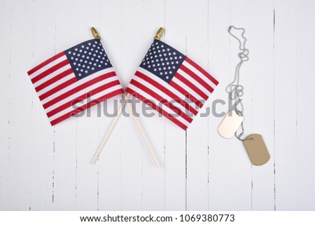 Military Dog Tags and American Flags on white wood background. 