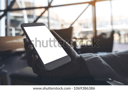 Mockup image of hand holding white mobile phone with blank desktop screen 