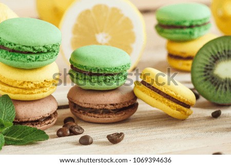 Green, yellow and brown french macarons with kiwi coffee beans and mint decorations, soft focus background