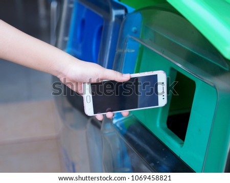 Female hands are dropping the old cell phone into the trash. Royalty-Free Stock Photo #1069458821