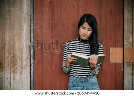 Hipster woman teenager standing enjoy reading book with wooden background.