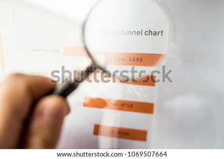 Male hand pointing with a pencil at a Sales Funnel chart printed on a white sheet of paper during a marketing meeting.